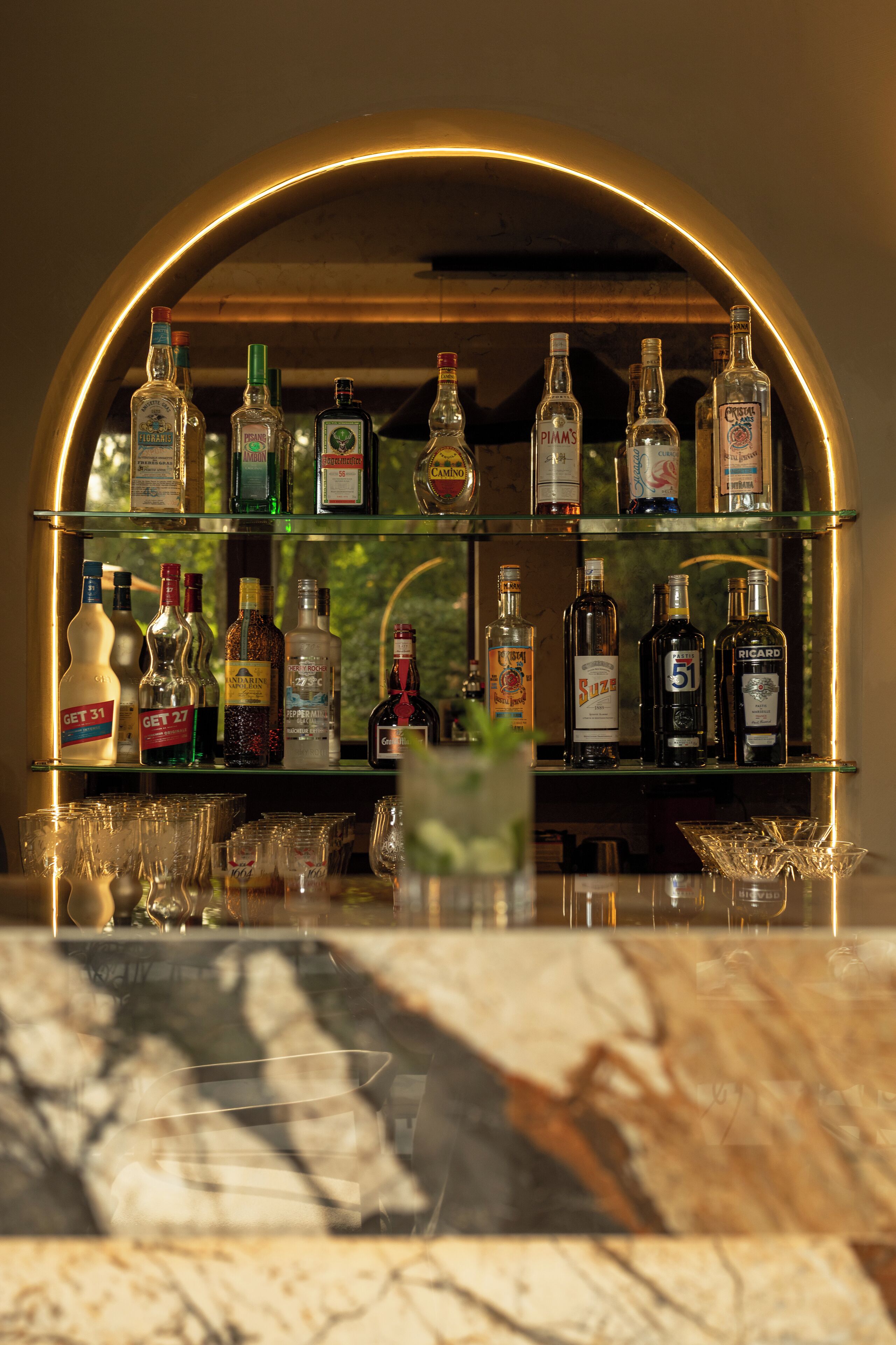 Un espace bar avec de nombreuses bouteilles d’alcool et des verres disposés sur des étagères.