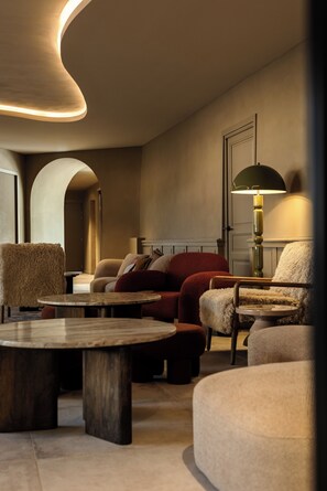 A modern lounge area with a curved ceiling, plush seating, and a table.
