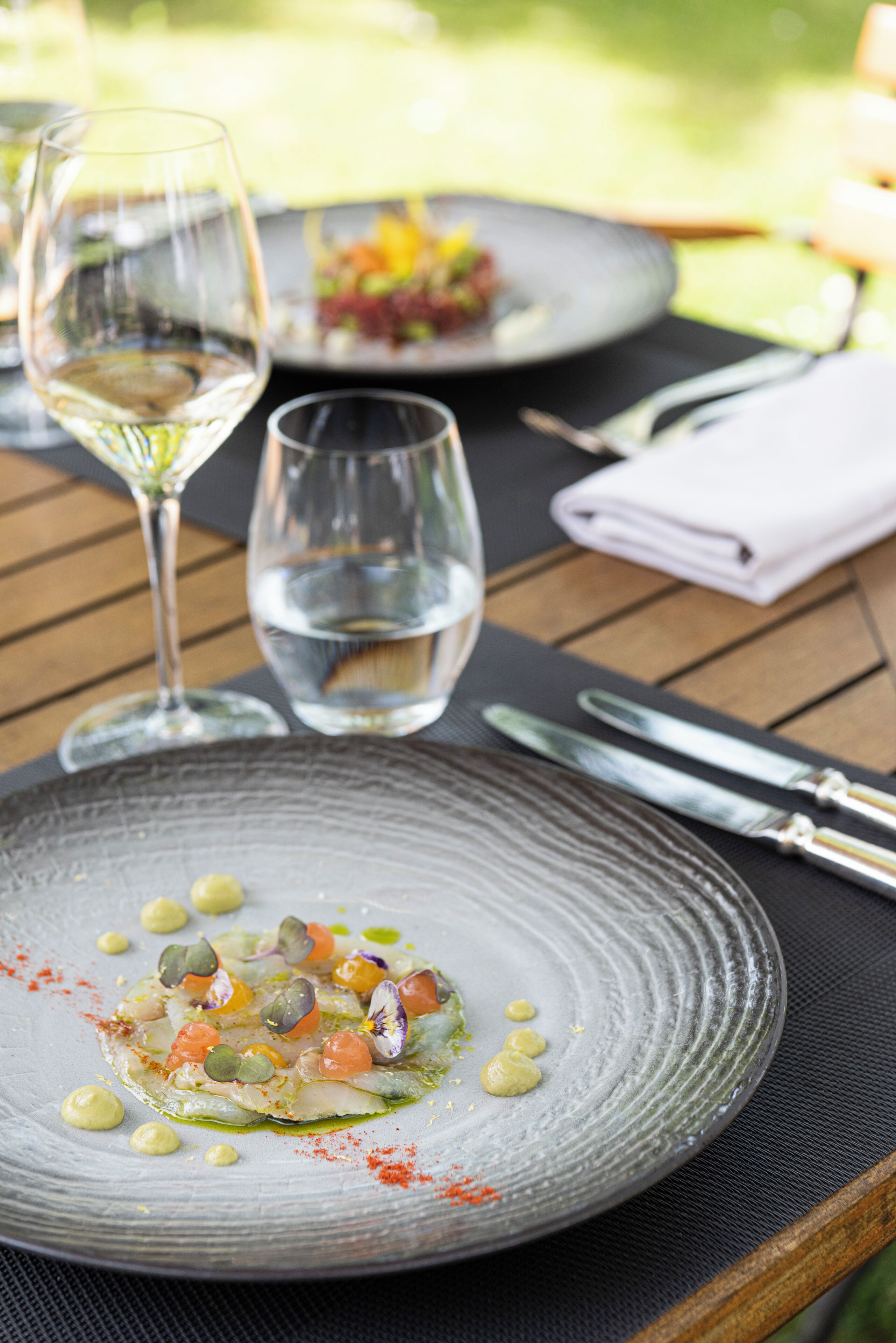 A dining table with a plate of food, a glass of water, and a wine glass.