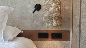 A bedroom with a bed, a round table, a textured wall hanging, and a wooden headboard.
