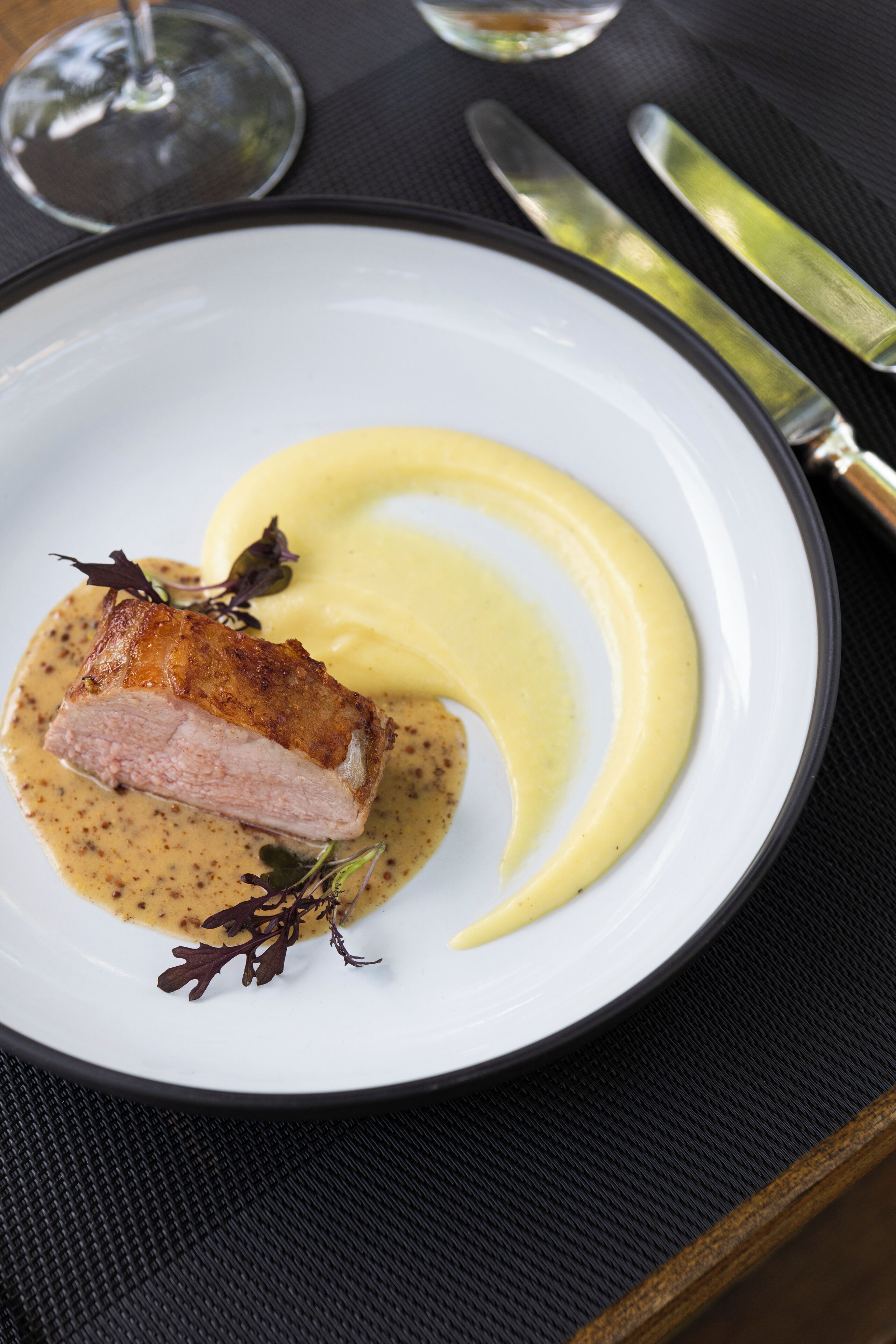 A plate of food with a piece of meat and mashed potatoes on a white plate.