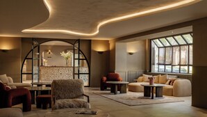 A spacious living room with a modern design, featuring a large sofa set, a coffee table, and a fireplace. - La Maison Chabran - Hôtel Restaurants (Pont-de-l'Isere)