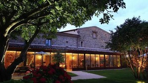 A stone building with a glass extension, surrounded by greenery and a well-maintained lawn. - La Maison Chabran - Hôtel Restaurants (Pont-de-l'Isere)
