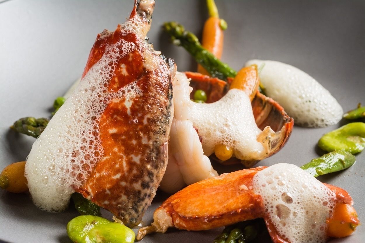 Un plat composé de chair de crabe et d’asperges, présenté dans une assiette.