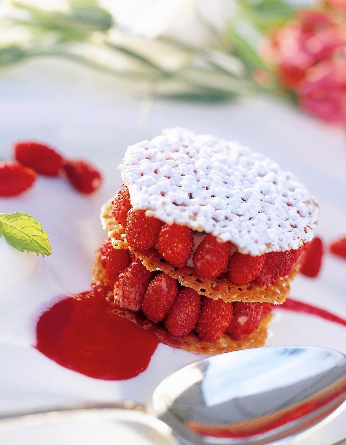 A dessert with strawberries and a white topping, served on a white plate with a spoon.