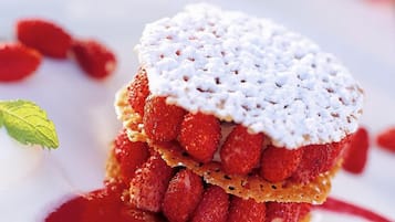 A dessert with strawberries and a white topping, served on a white plate with a spoon.