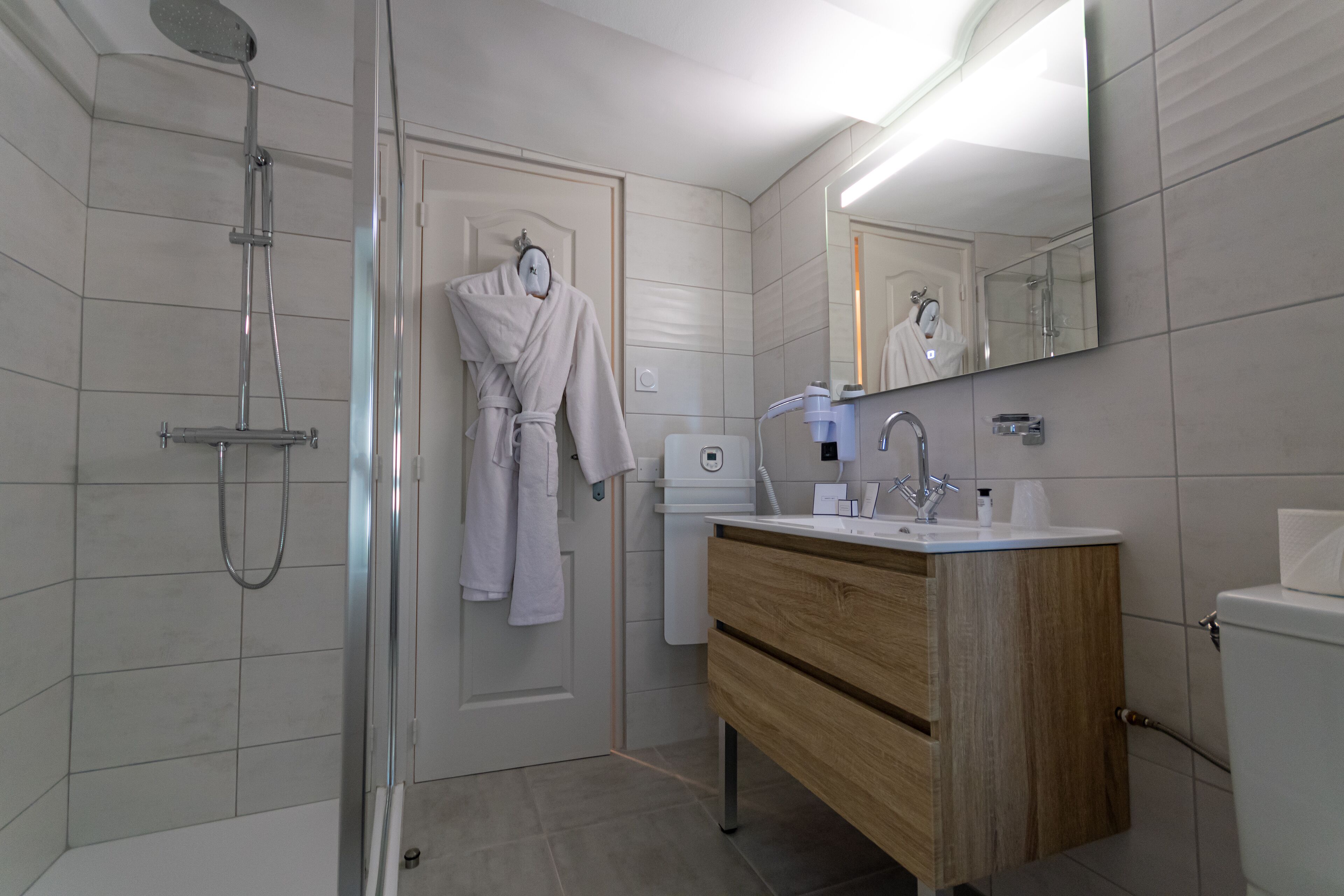 A modern bathroom with a glass-enclosed shower, a wooden vanity with a sink, and a mirror above the vanity.