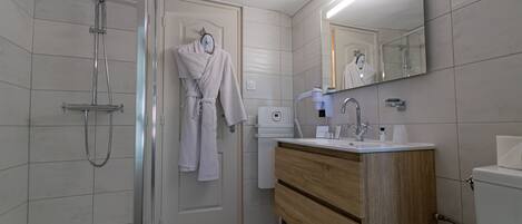 A modern bathroom with a glass-enclosed shower, a wooden vanity with a sink, and a mirror above the vanity.