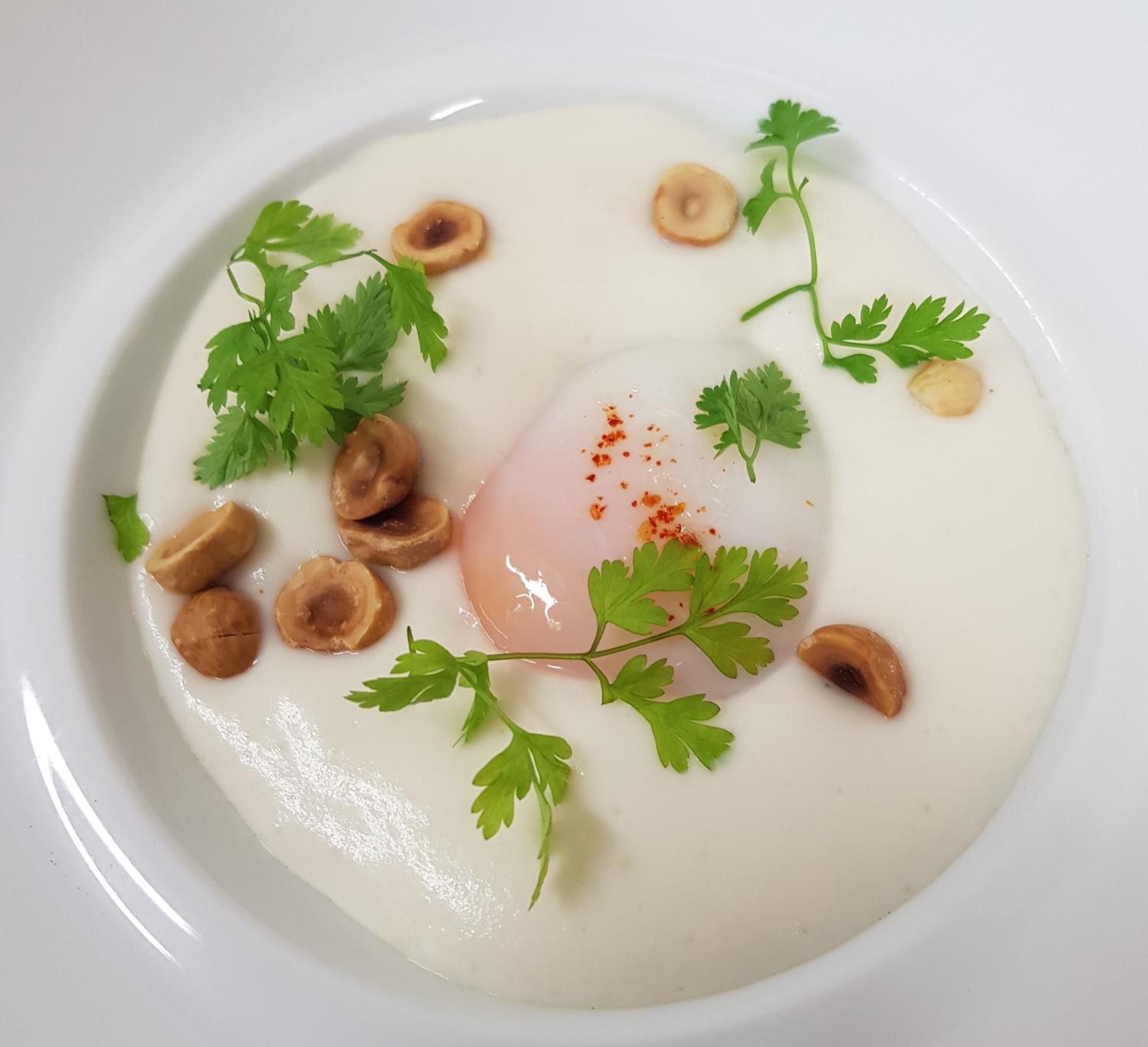 Une assiette blanche contenant un œuf poché, des champignons et une garniture de persil.