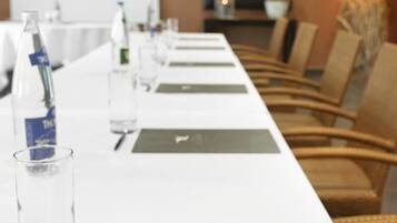 A conference room with a long table, chairs, water bottles, glasses, and a presentation screen.