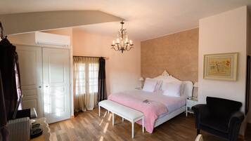 A bedroom with a bed, a bench, a chair, a desk, and an air conditioning unit.