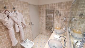 Een badkamer met twee wasbakken, een bidet en handdoeken aan haakjes.