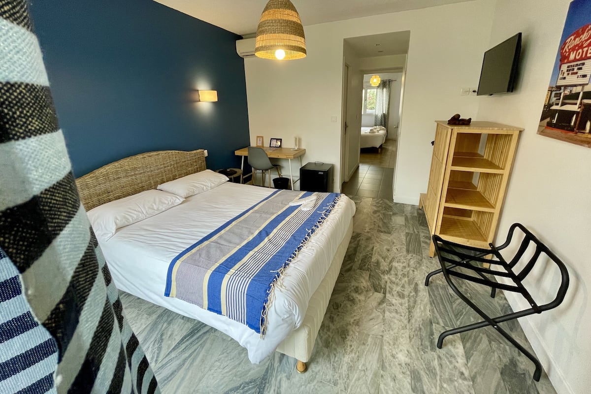 Ein Hotelzimmer mit einem Bett, einem Schreibtisch, einem Stuhl, einem Fernseher und einem Kleiderschrank.