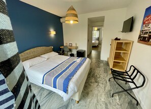 Une chambre d’hôtel comprenant un lit, un bureau, une chaise, une télévision et une armoire.