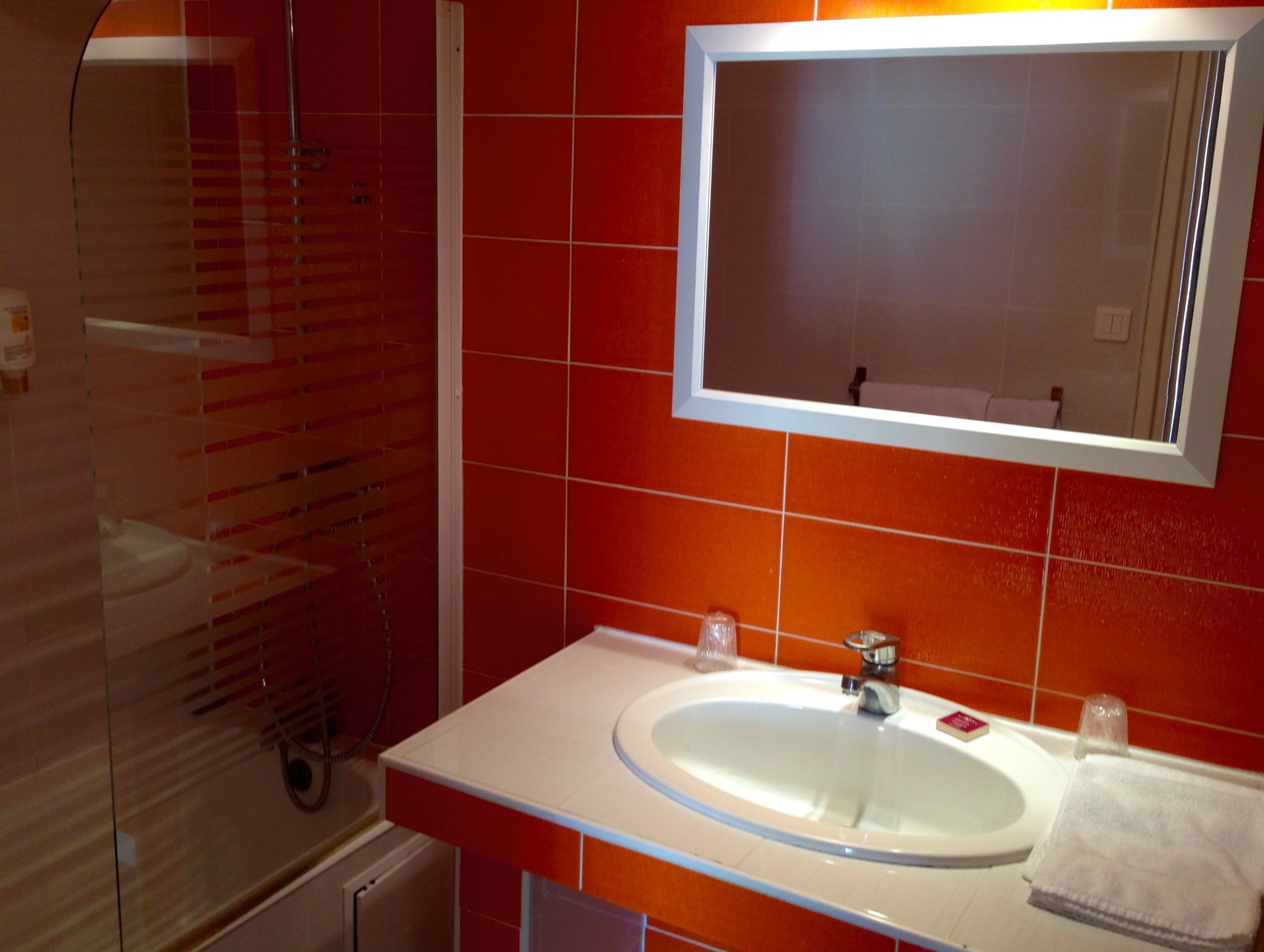 A bathroom with a white sink, a mirror, and red tiles.