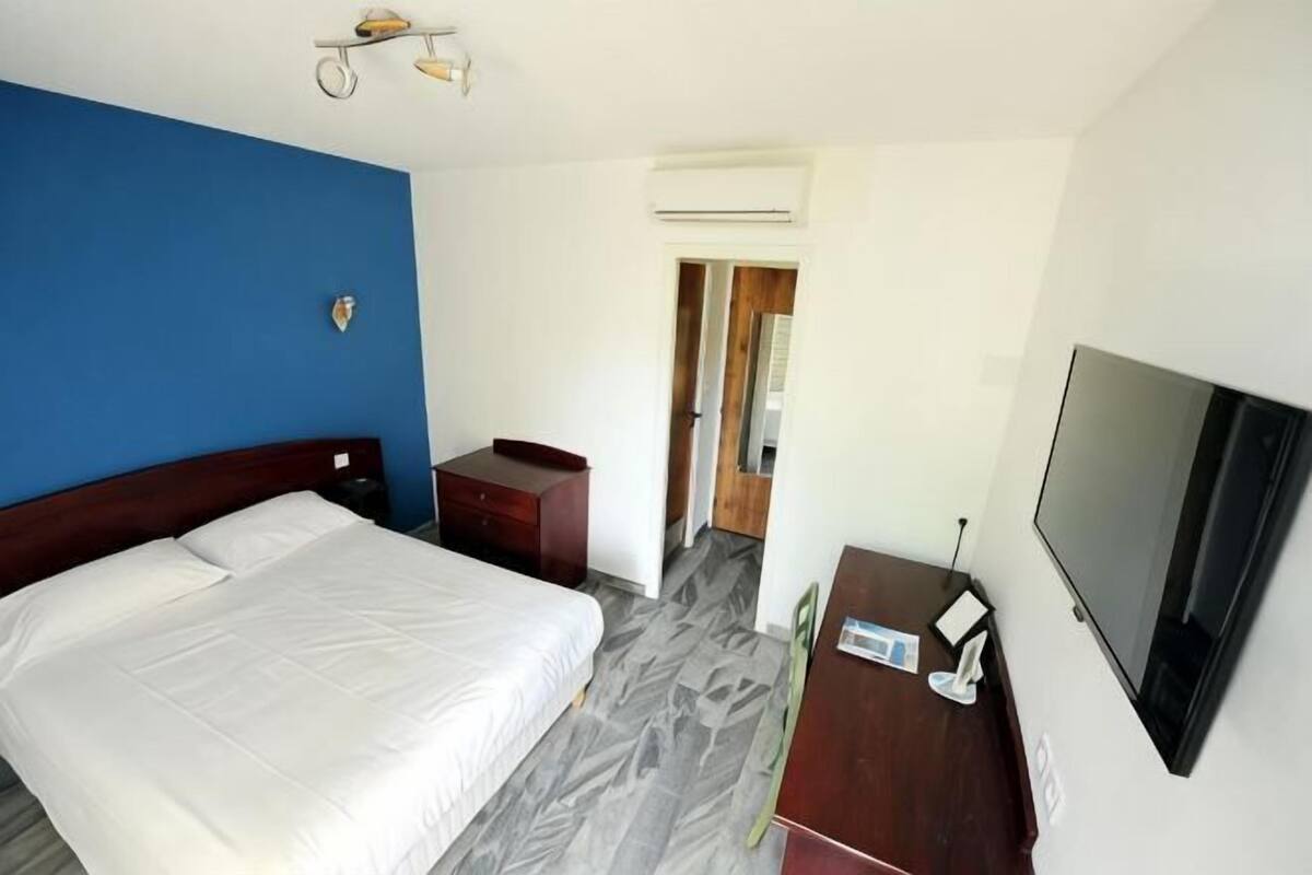 Ein Hotelzimmer mit einem Bett, einem Schreibtisch, einem Stuhl, einem Fernseher und einer Klimaanlage.