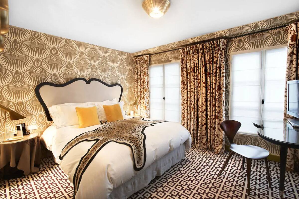 A hotel room with a large bed, a round table, and patterned curtains.