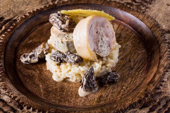 Un plato de madera con una porción de carne, arroz y champiñones.