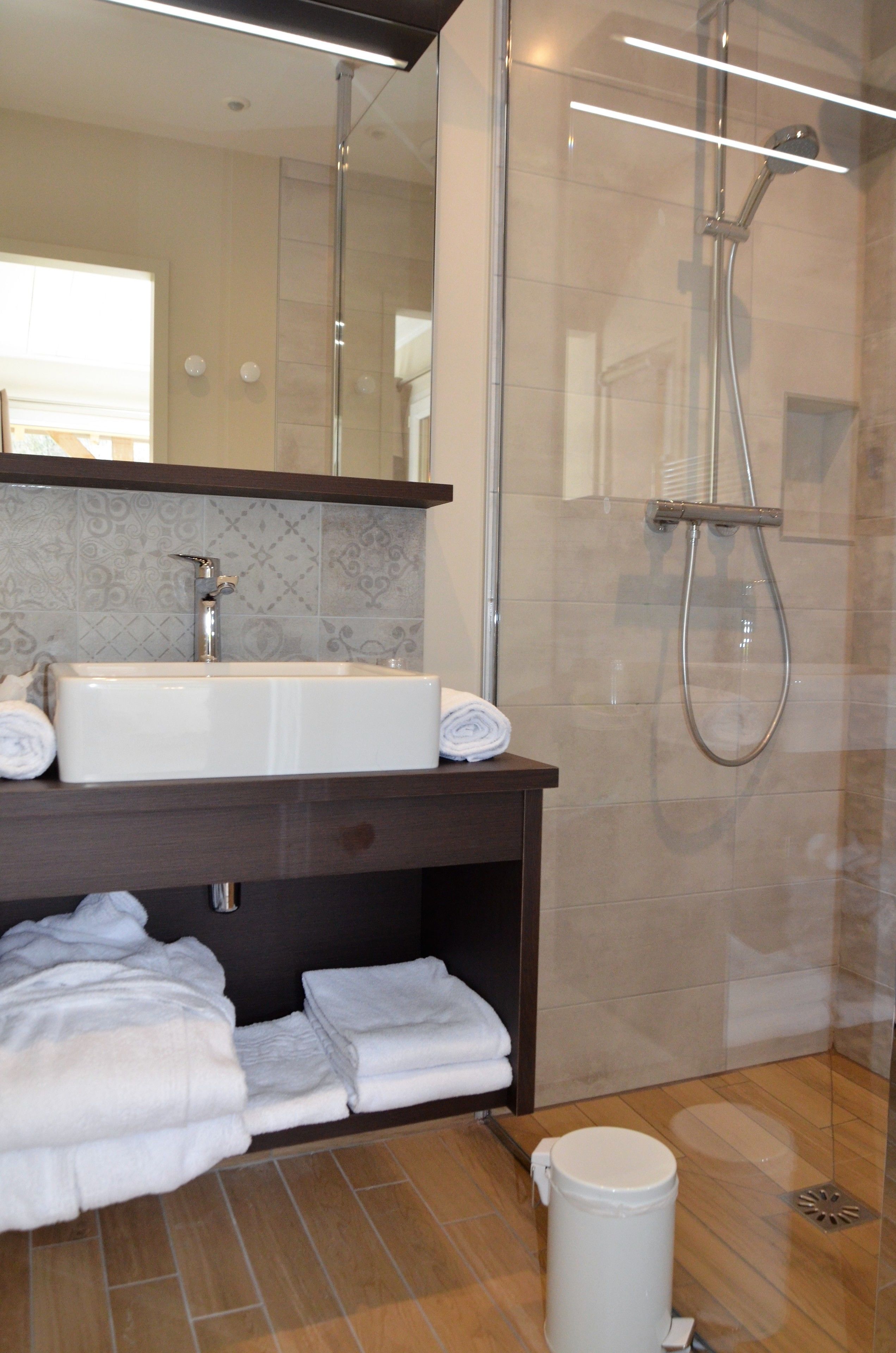 Un baño moderno con un lavabo grande, espejo y ducha.