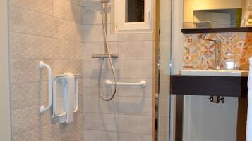 A modern bathroom with a glass shower enclosure, a small window, and a sink with a mirror above it.