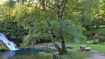 Un entorno exterior tranquilo con una cascada, un estanque y un muro de piedra.