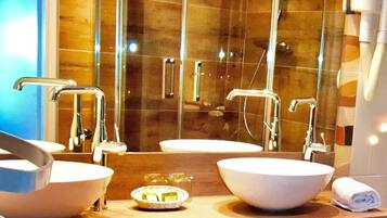 A modern bathroom with two sinks, a glass shower enclosure, and a towel rack.