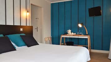 Habitación de hotel con cama, escritorio con lámpara, televisor y pared a rayas azules.