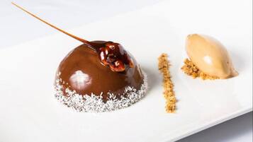Un postre con una capa caramelizada, una cucharada de crema y espolvoreado de migas sobre un plato blanco.