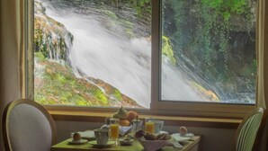 A breakfast table with a view of a waterfall through a window. - Castel Damandre (Les Planches-pres-Arbois)