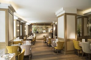 Un restaurante con barra, piso de madera y sillas estampadas de color amarillo.
