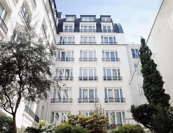 Un edificio de varios pisos con balcones, ventanas grandes y fachada blanca.
