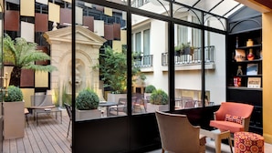 A modern interior with a wooden deck, seating area, and a view of the outside. - Hotel Rochester Champs Elysées (Paris)