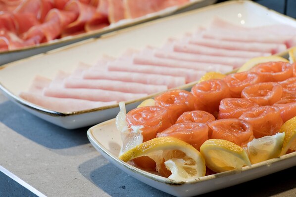 A plate with sliced salmon and lemon wedges. - Hotel Rochester Champs Elysées (Paris)
