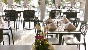 Un restaurante con mesas dispuestas para comer, sillas y un florero sobre la mesa.