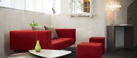 A modern living room with a red sofa, a small table, and a green vase.