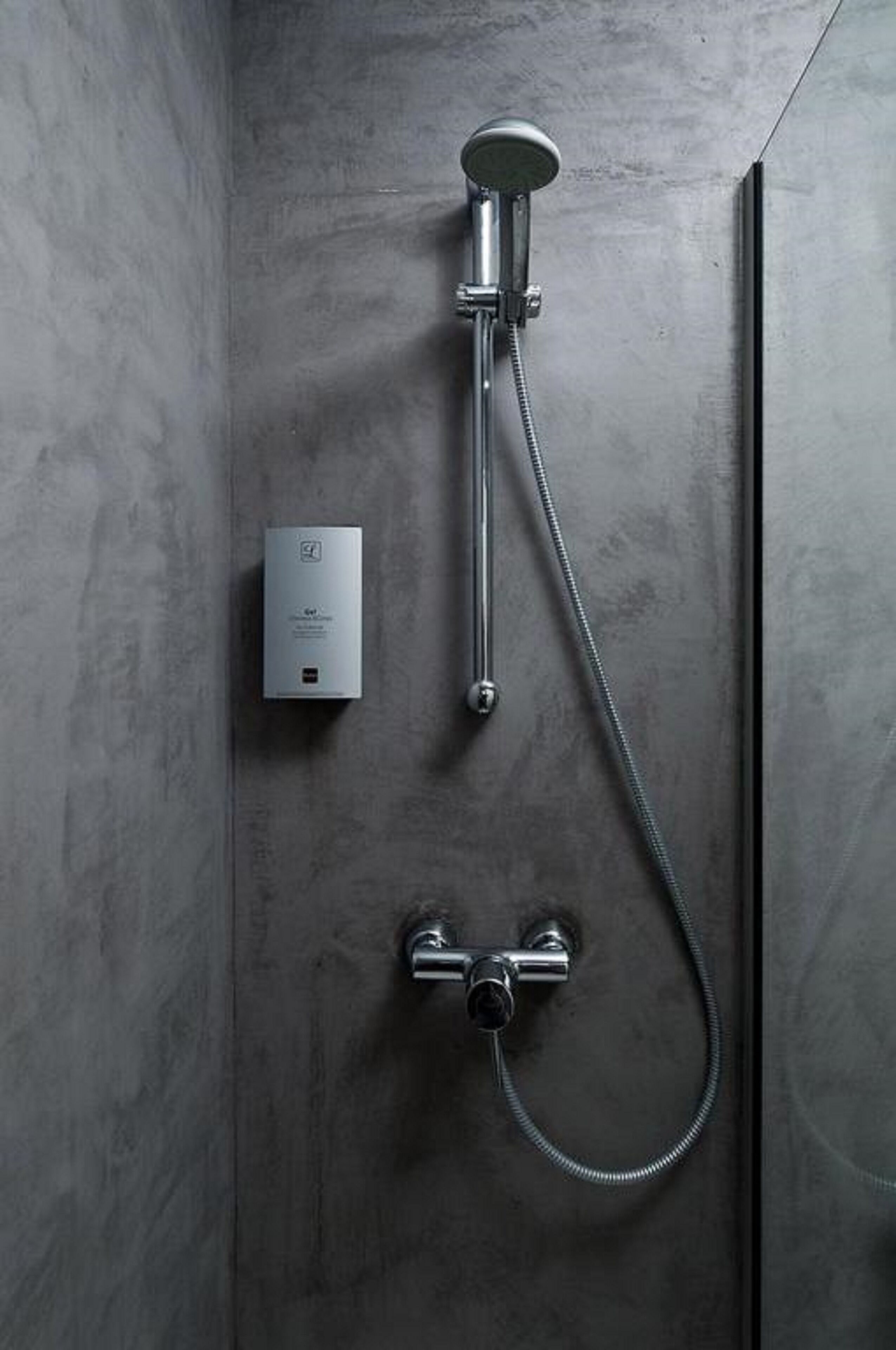 Ducha moderna con cabezal de ducha de mano y panel de control en la pared.
