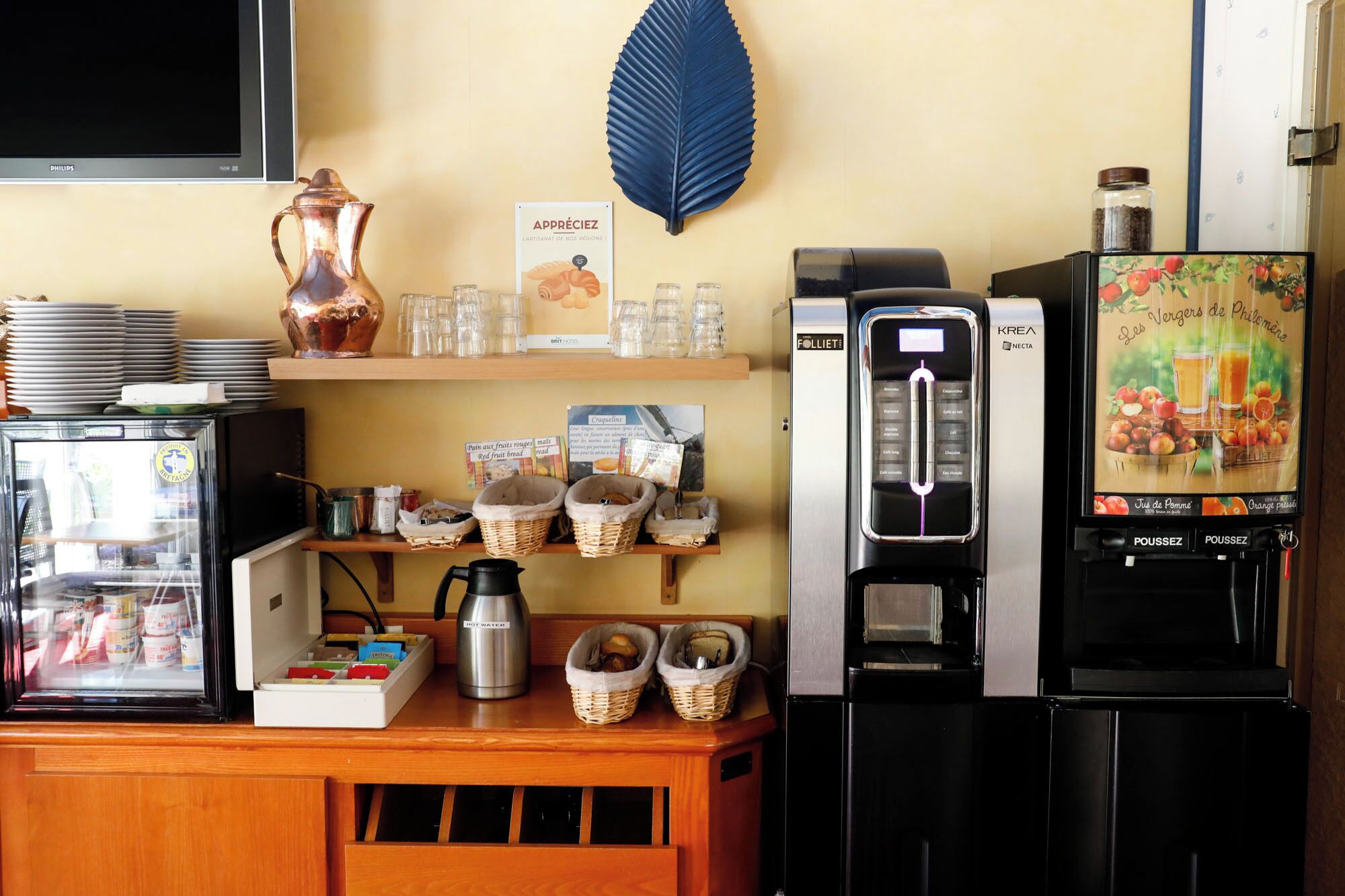 Una estación de café con una máquina de café, un refrigerador y una exhibición de granos de café y productos de pastelería.