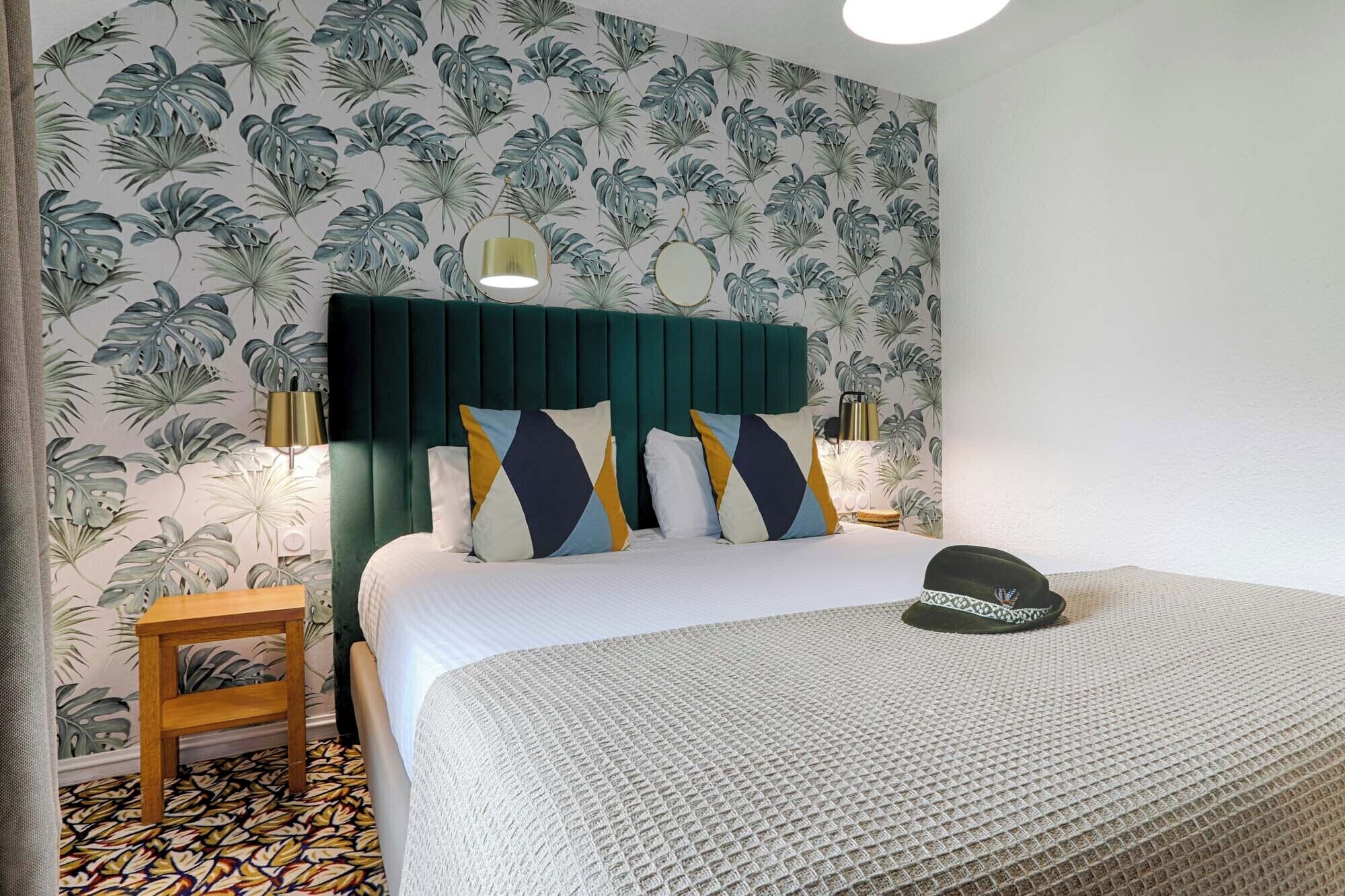 Un dormitorio con una cama, una mesita de noche, una lámpara y un sombrero decorativo sobre la cama.