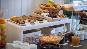A buffet with various food items including fruits, pastries, and beverages.
