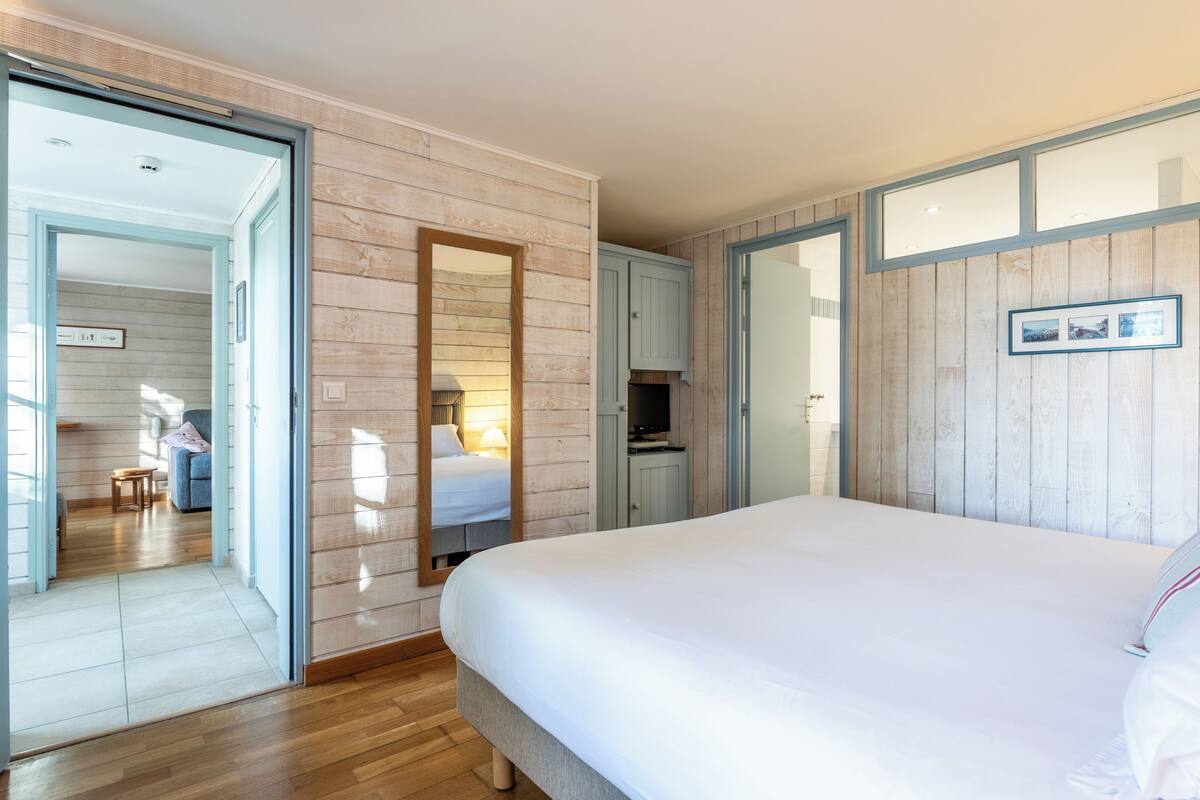 A bedroom with a large bed, a mirror, a wardrobe, and a television.