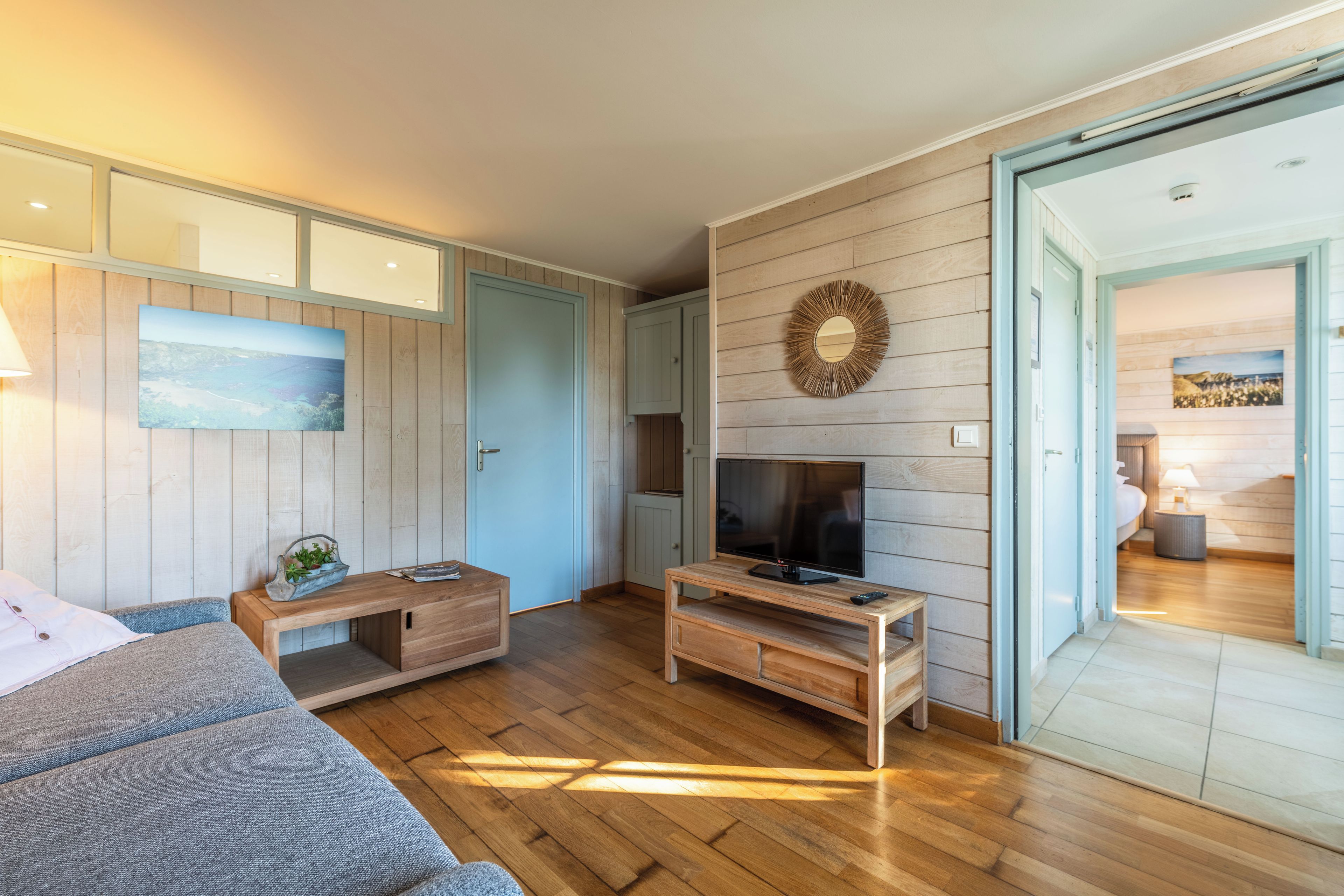 Un salon chaleureux avec un canapé, une table basse et un téléviseur posé sur un meuble en bois.