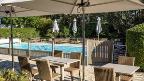 An outdoor patio area with wicker furniture, a pool, and a signboard.