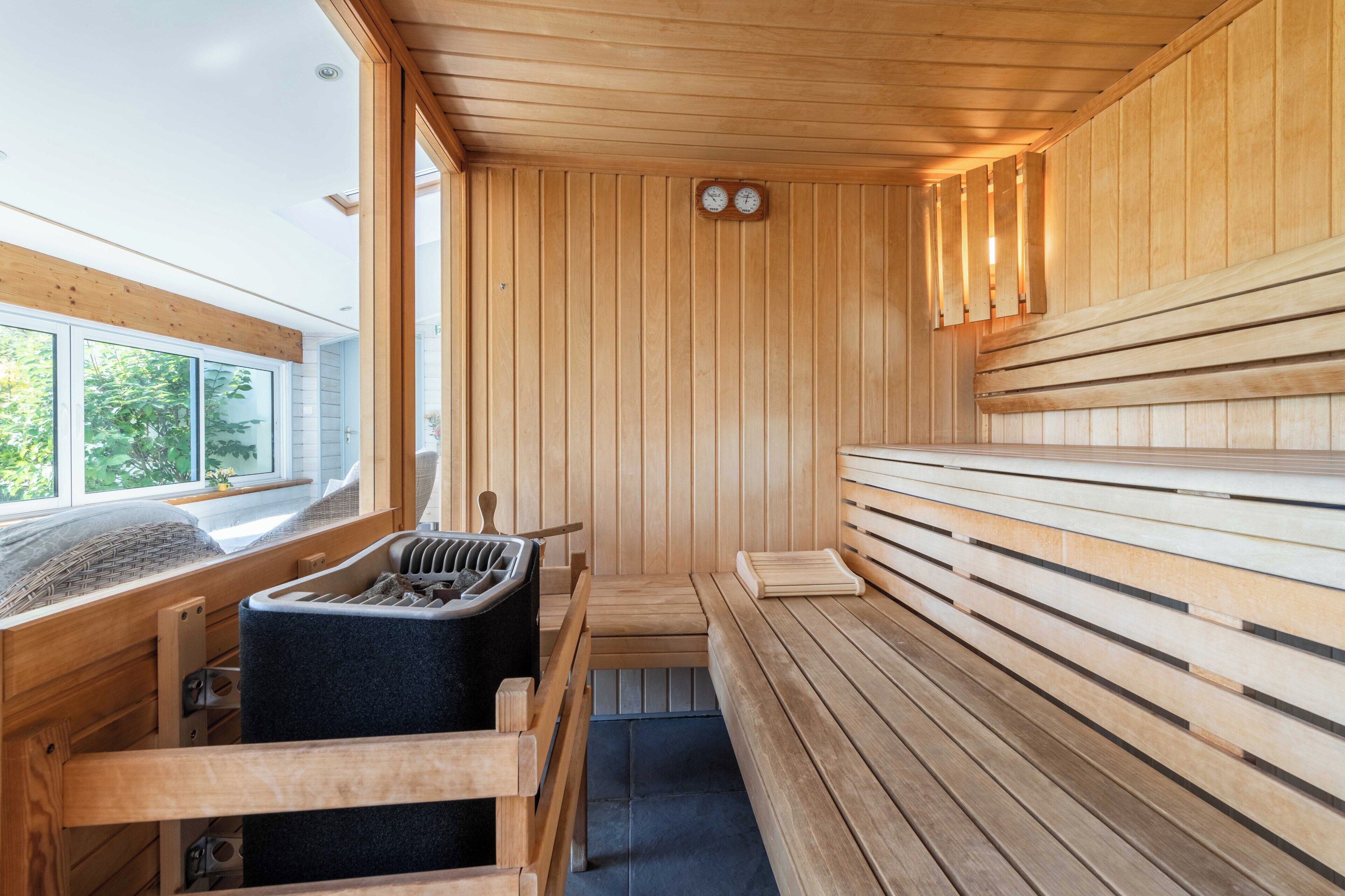 A sauna with wooden benches and a bench seat, a bench with a towel, and a bench with a towel.