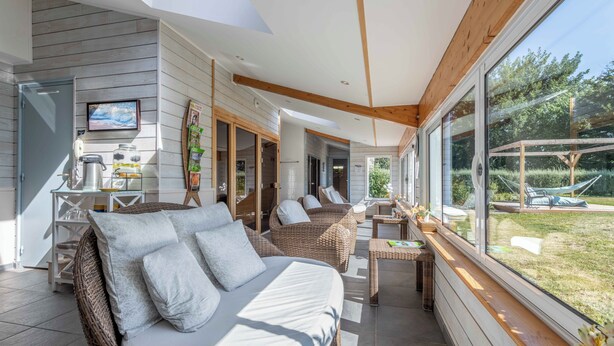 A modern, well-lit room with a large window, wicker furniture, and a view of the outdoors.