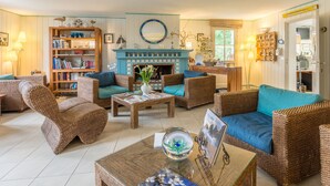 A cozy living room with wicker furniture, a fireplace, and a bookshelf.