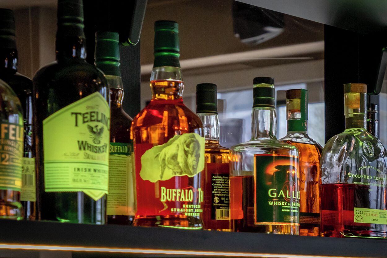 Verschillende flessen whisky op een plank.