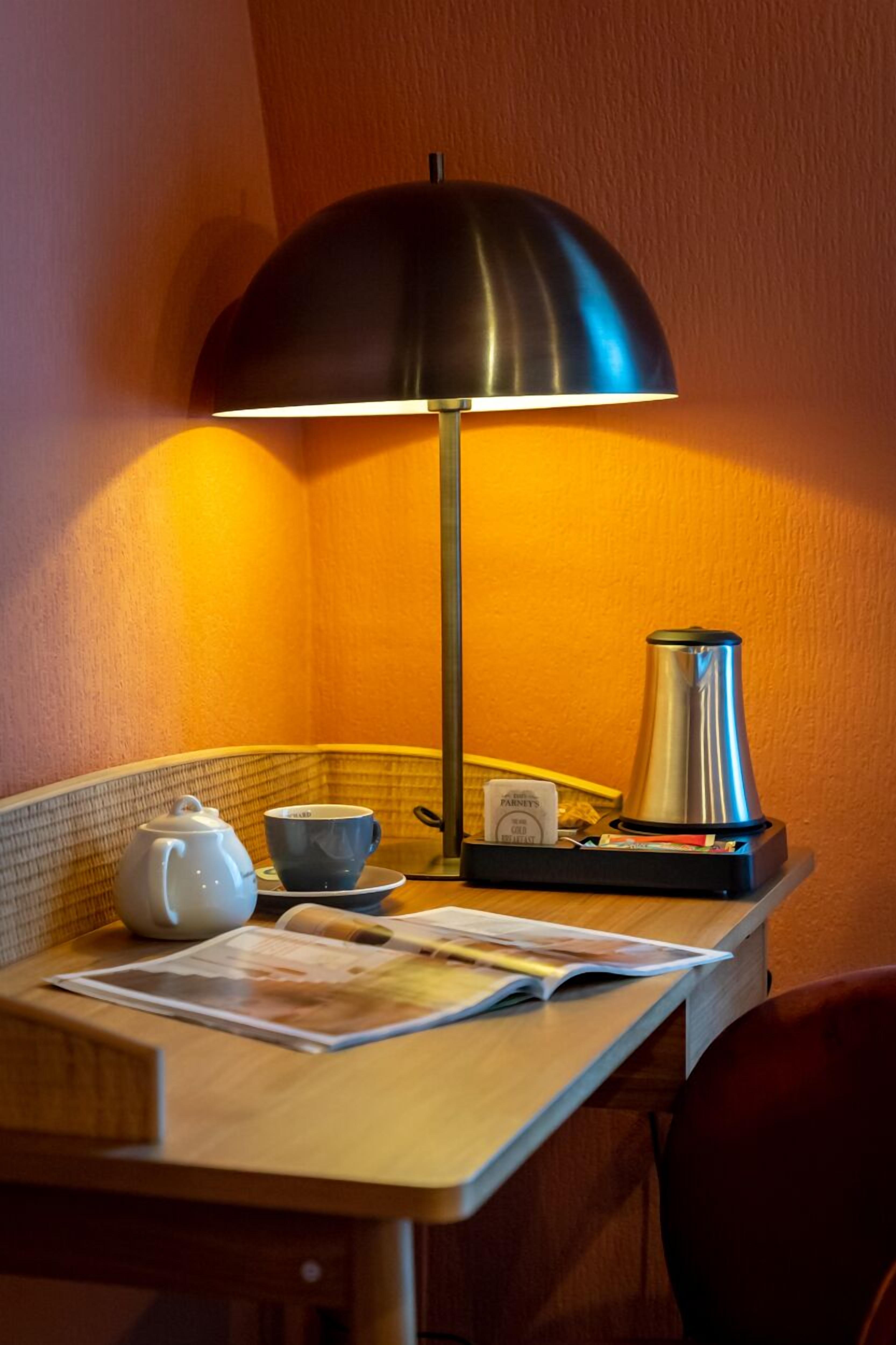 Ett bord med en kaffebryggare, en kopp, en tekanna och en meny.