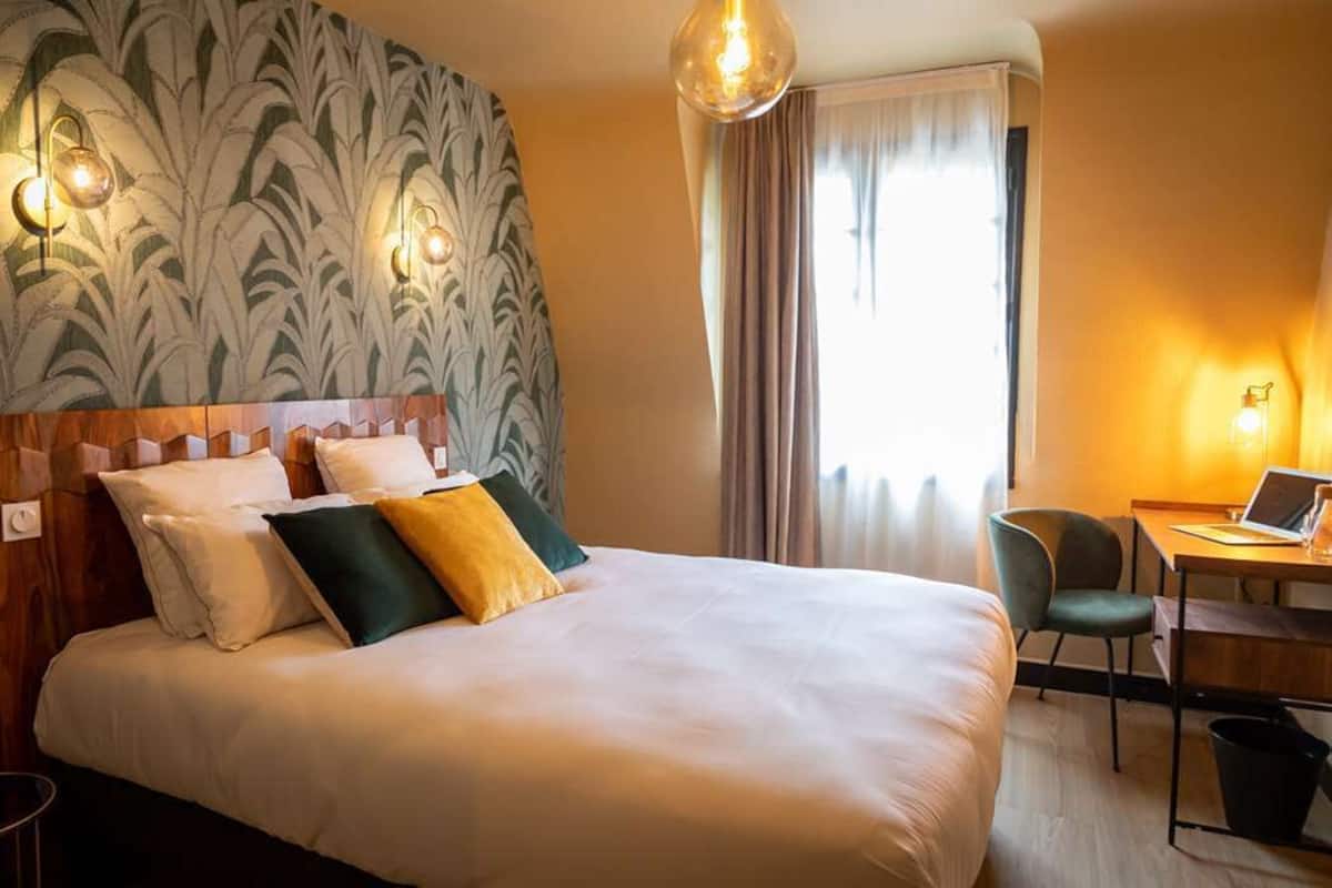 Habitación de hotel con una cama grande, un escritorio con una computadora portátil y una silla.