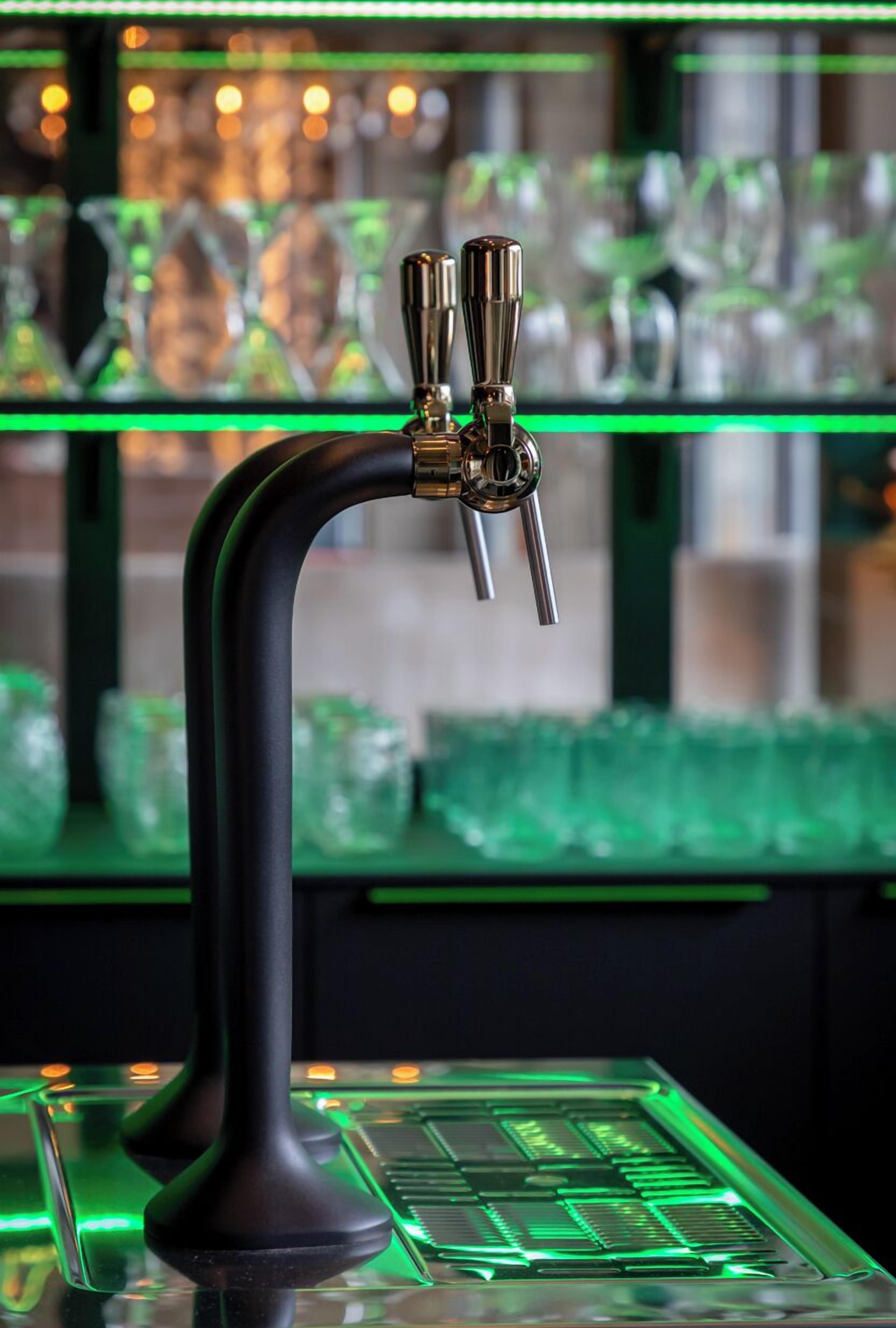 A bar with a black faucet and illuminated green lights.