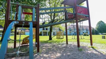 Ein Spielplatz mit Klettergerüst, Rutschen und einem überdachten Bereich.